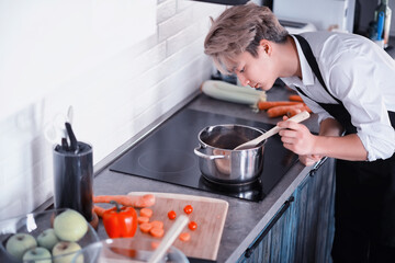 Asian cook in the kitchen prepares food in a cook suit