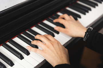 Fototapeta na wymiar Close up of woman's hands playing piano by reading sheet music. Selective focus