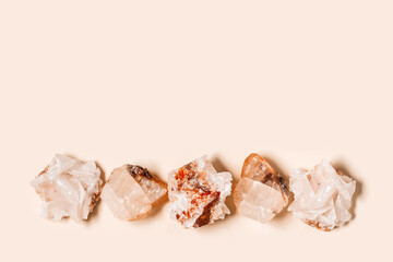 Flat lay bright beige quartz crystals on peach color background. Magic and healing crystal, gem...