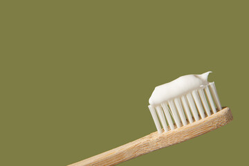 Bamboo toothbrush with toothpaste on a gentle green background with copy space. Close-up view with...