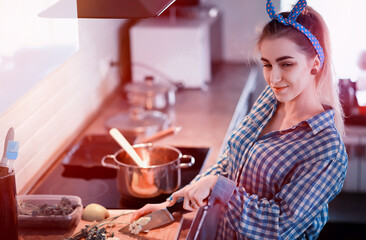 A cute young girl in the kitchen prepares food