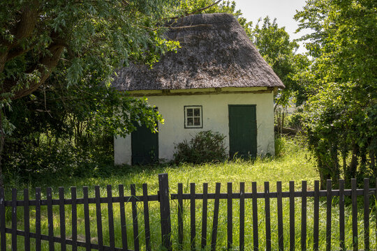 Kleines Reetdachhaus an der Ostsee mit Zaun in Front