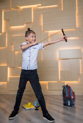 funny boy aiming at slingshot with a schoolbag and a globe