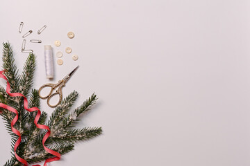 Accessories for sewing in a Christmas composition with a branch of a fir tree. Top view, flat position.