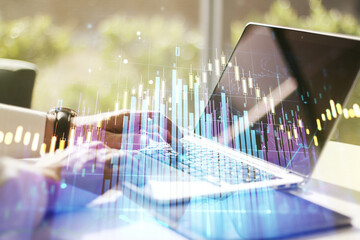 Abstract creative financial graph with hand typing on laptop on background, financial and trading concept. Multiexposure