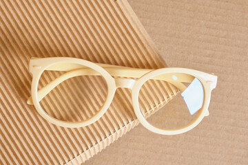 trendy fashion plastic eye glasses on box corrugated cardboard, beige background
