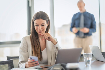 Businesswoman text messaging and using laptop while working at the office