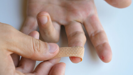 Male applying band aid patch to injured sore fingers. Man putting medical adhesive bandage tape...