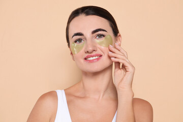 Beautiful woman with under eye patches on beige background