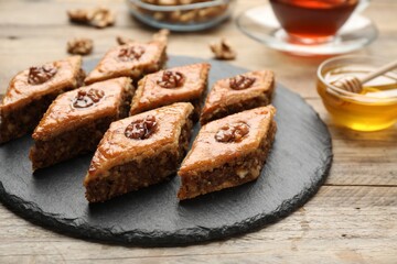 Obraz na płótnie Canvas Delicious honey baklava with walnuts served on wooden table, closeup