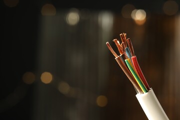 Cable with copper wires against blurred background, closeup. Space for text