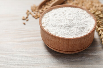 Bowl with wheat flour on wooden table, closeup. Space for text