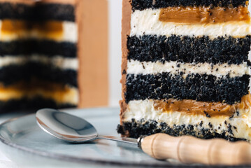 Cake and a piece cut off from it. The cake is decorated with Sweet chocolate macarons. A piece of cake on a plate pockmarked with a spoon.