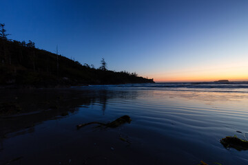 Fototapeta premium Sandy Beach on the West Coast of Pacific Ocean. Canadian Nature Landscape Background. Sunny Sunset Twilight. Cox Bay, Tofino, Vancouver Island, BC, Canada.