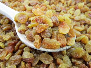     yellow golden raisins in wooden spoon