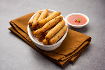 Fototapeta na wymiar crispy Rava Aloo fingers or Potato semolina fried finger sticks served with ketchup