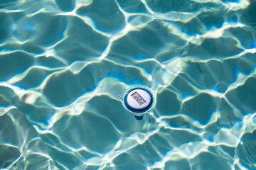 Digitales Poolthermometer schwimmt im im Pool und zeigt die Temperatur an.