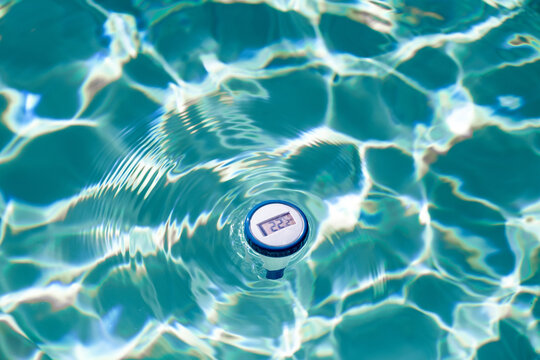 Digitales Poolthermometer schwimmt im im Pool und zeigt die Temperatur an.