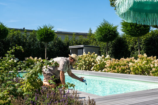 Mann mit Strohhut, im Sommer, pr&uuml;ft die Temperatur des Pool.