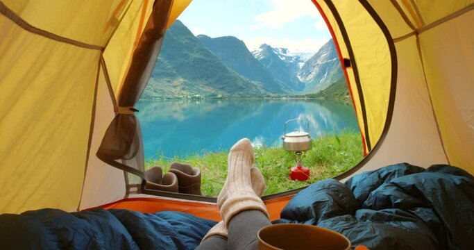 Environmental tourist relaxing in a camping tent, drinking coffee with an open nature view mountain background. Adventure, eco and hippy woman, camper or traveler calm and relaxed on getaway retreat