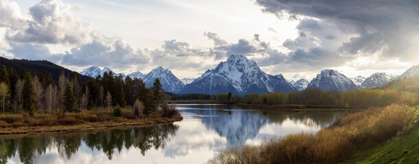 Fototapeta na wymiar River surrounded by Trees and Mountains in American Landscape. Snake River, Oxbow Bend. Spring Season. Grand Teton National Park. Wyoming, United States. Nature Background Panorama. Sunset