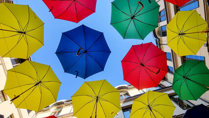 multi color umbrellas as street outdoor decoration, bright blue sky background 