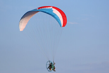 Paramotor pilot flying in a blue sky	