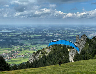 Gleitschirmflieger beim Start an der Kampenwand mit Blick ins Chiemgau, Alpen, Bayern, Deutschland