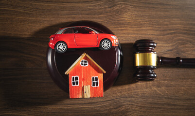 Judge gavel with a house model and toy car on the wooden table.