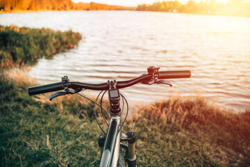 Fototapeta na wymiar Mountain bike on a lake shore. Summer sunset adventures in the countryside. Using a bicycle in rural area.