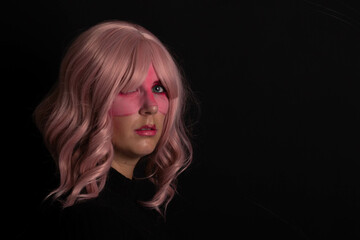 Modelo mirando a cámara cara maquillada, en estudio, peluca rosa