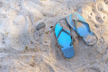 Summer vacations on the beach, blue flip-flops in the sand in a tourist resort on the Baltic Sea in...