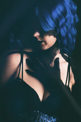 Modelo con mano y cara pintada, pelo azul, en estudio sobre fondo negro