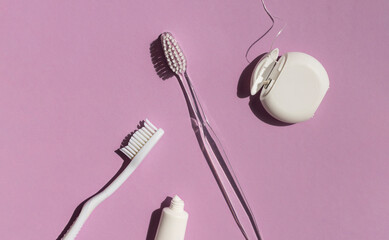 Dental care concept composition with toothbrush, tooth floss and toothpaste on the bright violet background.	 - obrazy, fototapety, plakaty