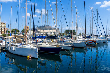 Obraz premium boats and yachts on pier in marine city port with masts and bulidings and blue sky on background