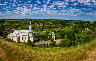 Catholic church in the Ukrainian village of Zinkiv. Rural landscape with a beautiful church on a summer day.