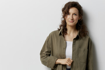 Cute smiling happy curly beautiful woman touches casual khaki green shirt posing isolated on over white background. People Emotions Lifestyle concept. Fashion offer. Copy space