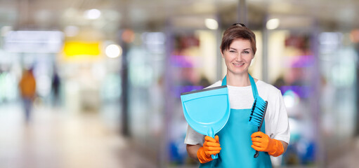 A cleaning lady with a dustpan for cleaning and a brush stands . - obrazy, fototapety, plakaty