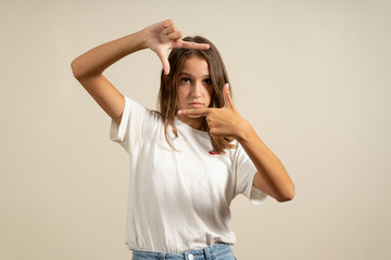 Teenage latin girl wearing casual white t-shirt smiling making frame with hands and fingers with happy face. creativity and photography concept