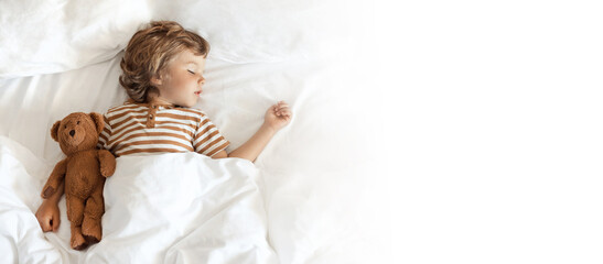 Banner with top view of cute little baby sleeping sweetly with bear toy on white clean bed clothes...