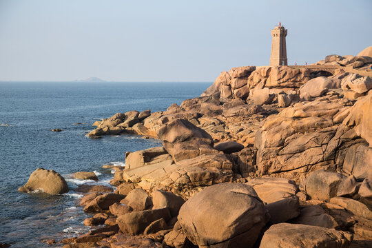 The lighthouse Men Ruz with bridge towering the extraordinarily colored stones and fantastically shaped rock formations at the Atlantic Ocean - the famous pink granite coast in Brittany, France