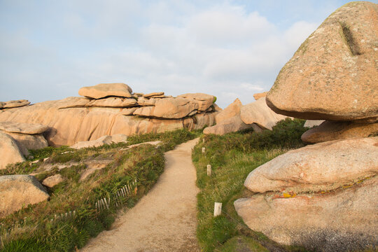 A walking trail winds among extraordinarily beautifully colored stones and fantastically shaped rock formations, edged by heather, gorse, mimosa, wild flowers - pink granite coast in Brittany, France