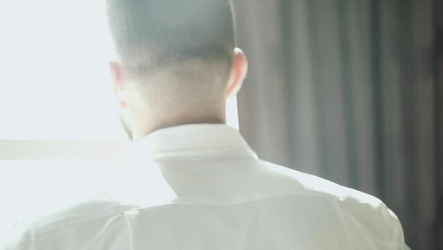 Back view of handsome man puts oa white shirt