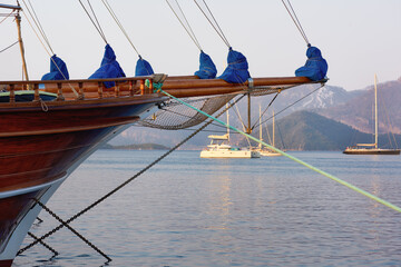 Wooden prow of a sailing ship. Bowsprit with tight ropes. Moored ship at anchor overlooking the sea...