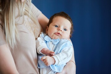 A small newborn baby boy in the arms of a woman. The concept of motherhood and childhood.