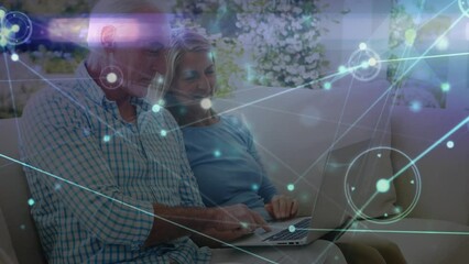 Animation of network of connections with light trails over senior caucasian couple using laptop - Powered by Adobe