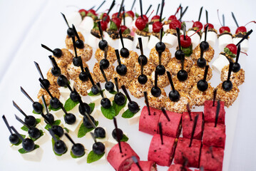 Beautifully decorated catering banquet table with different food snacks and appetizers with sandwich, caviar, fresh fruits on corporate party event or wedding celebration