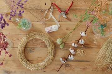 Florist making bouquet of dried flowers at wooden table, top view. Materials for making herbarium