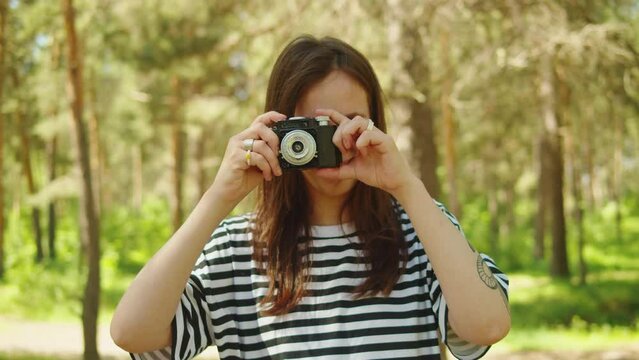 Woman taking photo in forest, tourist using camera , safe travel and explore, walking hiking tours, generation z lifestyle, teenager happy photographer.