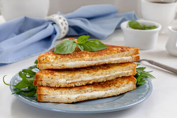 Stack of sliced fried sandwich with melted mozzarella on a plate. Italian grilled cheese sandwich Mozzarella in carrozza on white stone background.